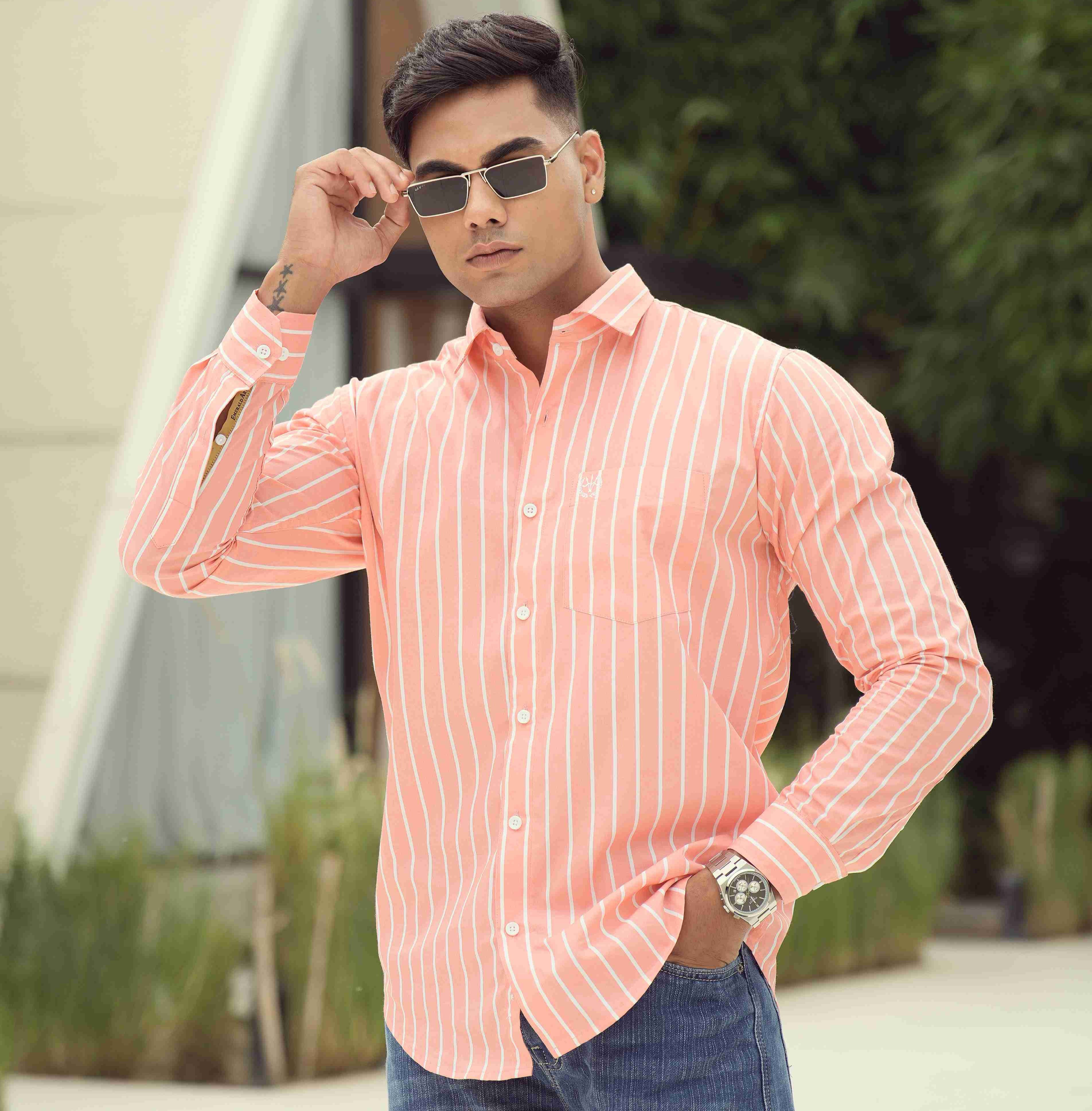 Man wearing a pink striped shirt and sunglasses outdoors