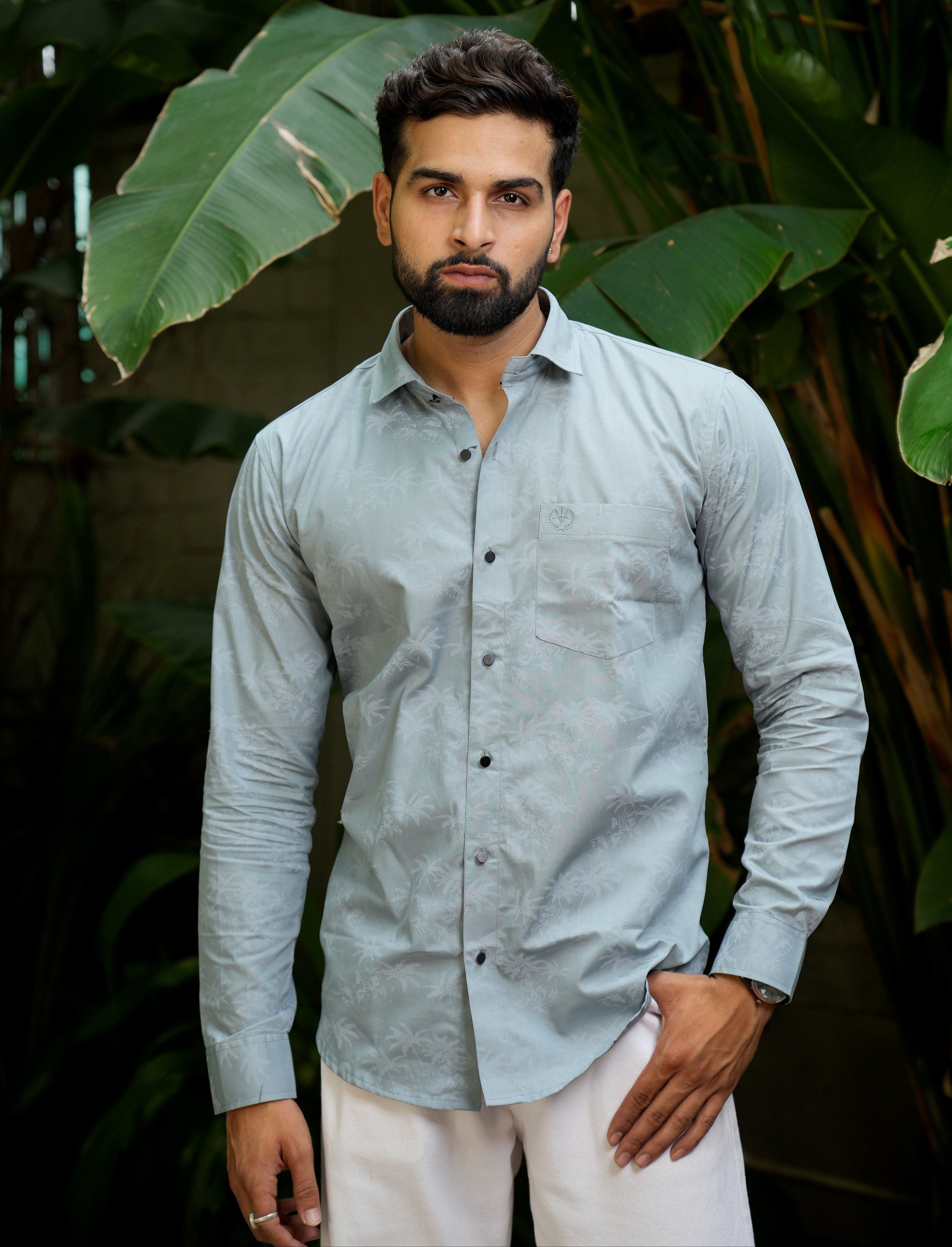 formal_shirt_-_Amerald_arrows Man wearing a light gray shirt standing among large green leaves