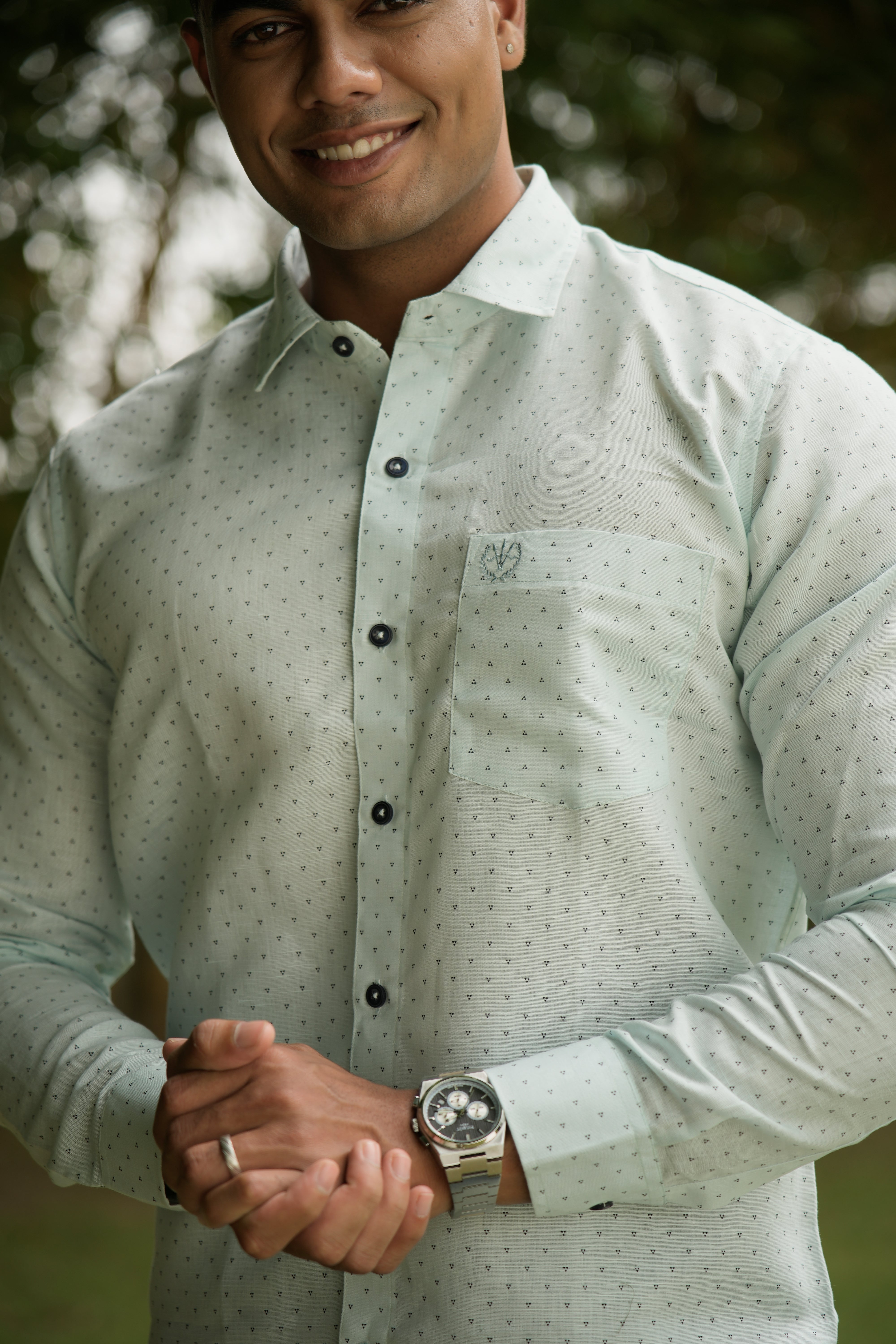 formal_shirt_-_Amerald_arrows Man wearing a light green shirt with a pattern, holding hands with another person outdoors.