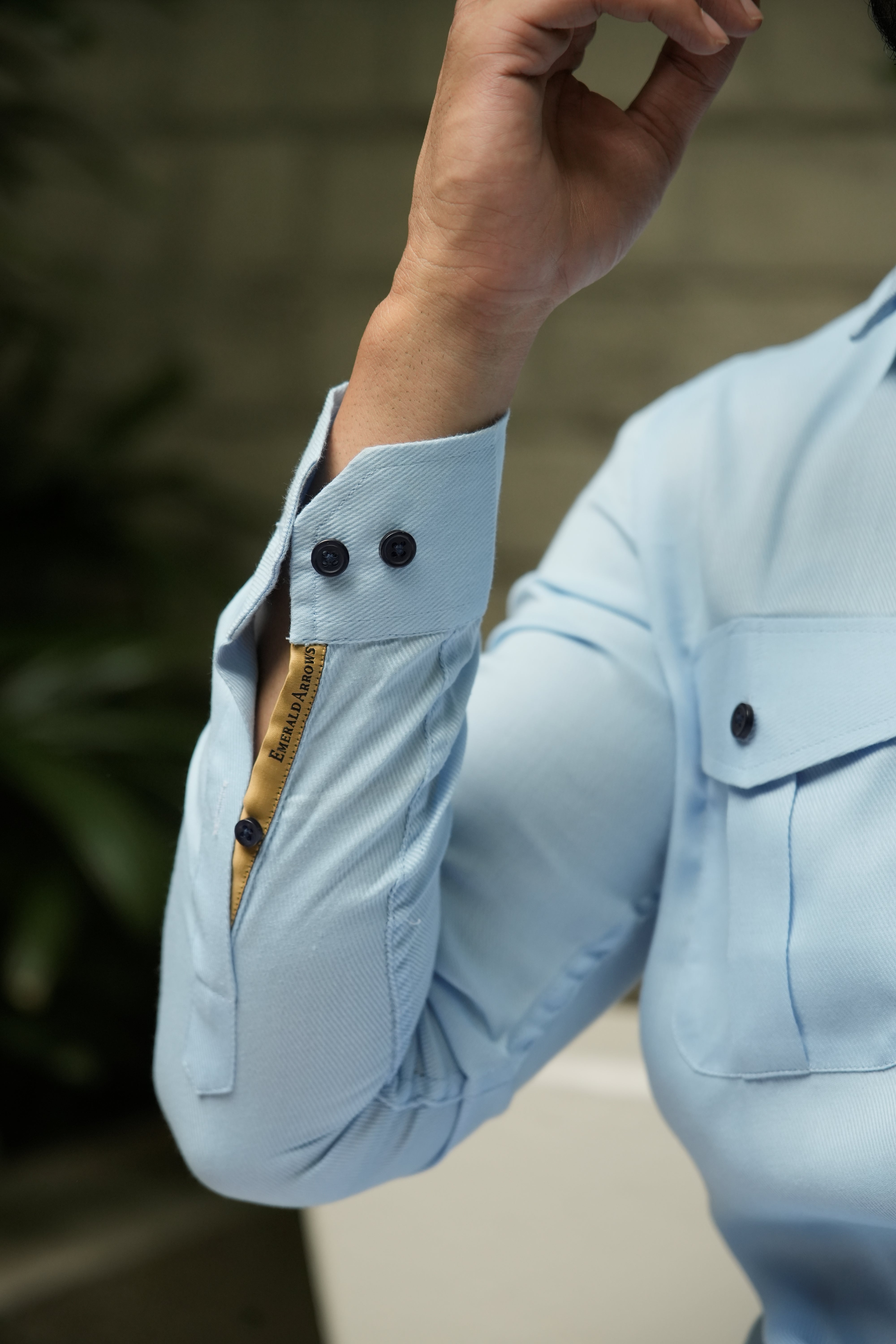 Light blue shirt with rolled-up sleeve and brand label on a blurred background